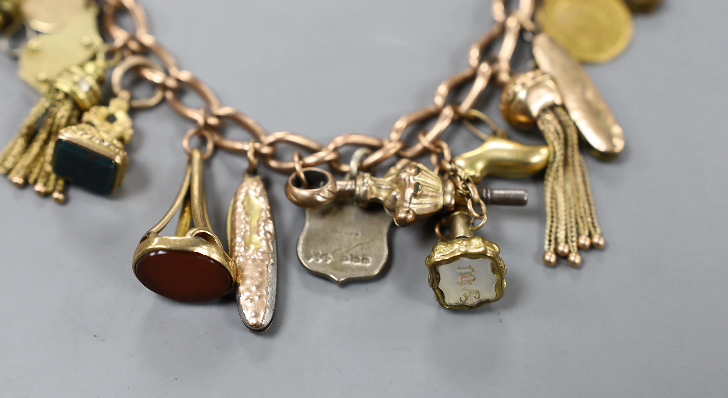 A 9ct charm bracelet, hung with assorted charms including two 9ct, silver and enamel, gilt metal and two gold coins gross weight 61.4 grams.